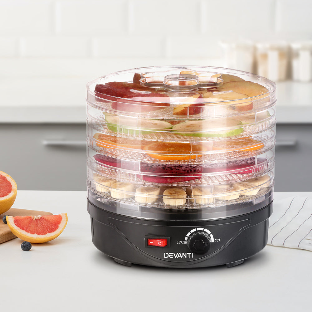 Food dehydrator with transparent trays drying assorted fruit slices on a kitchen countertop
