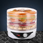 Electric food dehydrator with stacked trays drying sliced fruits on a marble counter