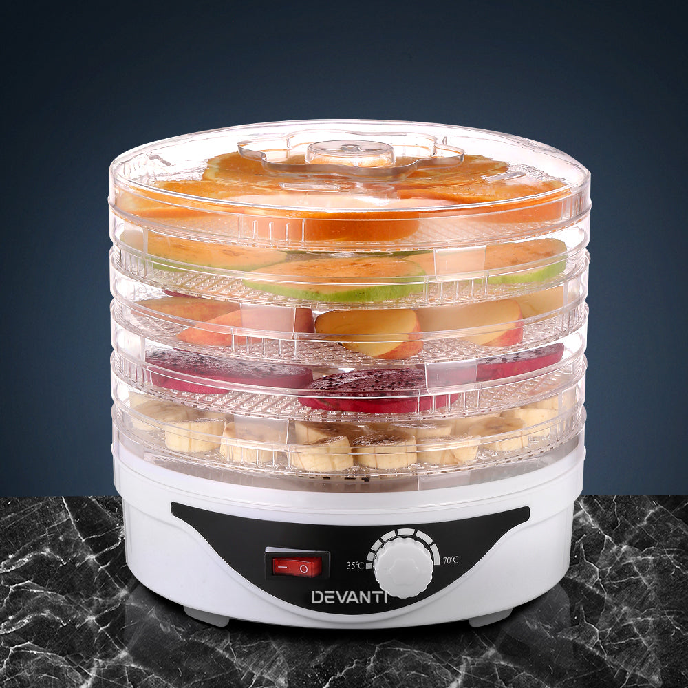 Electric food dehydrator with stacked trays drying sliced fruits on a marble counter